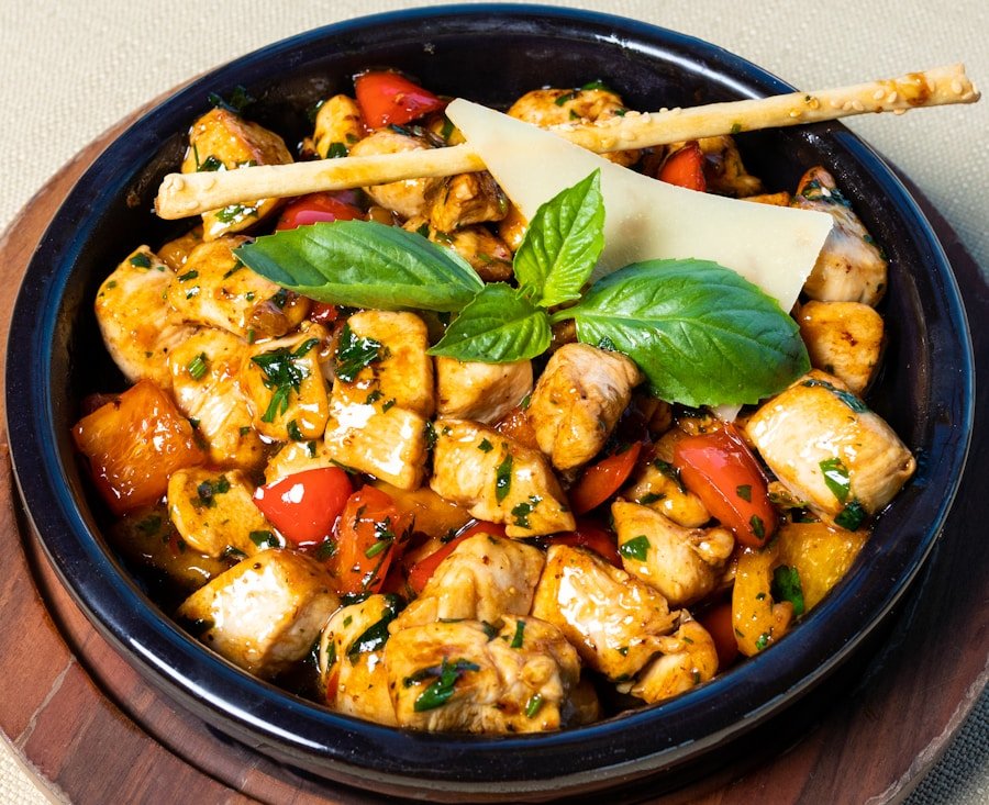 Flaming Kabob A black bowl filled with a colorful chicken stew containing herbs, red peppers, and cheese, garnished with fresh basil leaves and a breadstick. Commerce TWP, MI