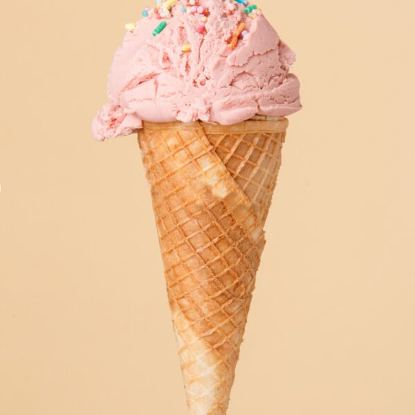 Cornet ice cream with a strawberry scoop on a colorful backgroun