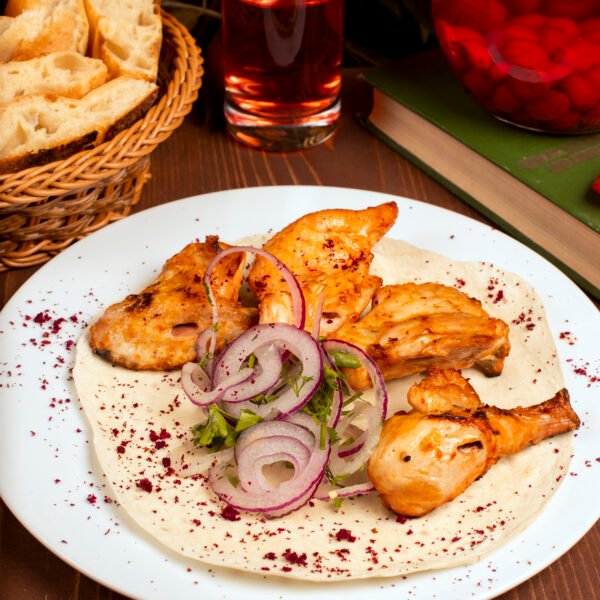 Grilled chicken wings kebab served with composto onion vegetable salad herbs white plate