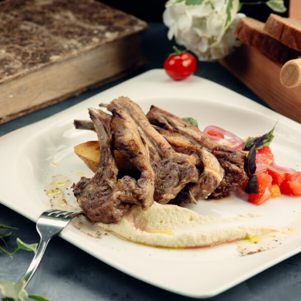 A plate of grilled lamb ribs with puree and fried potato