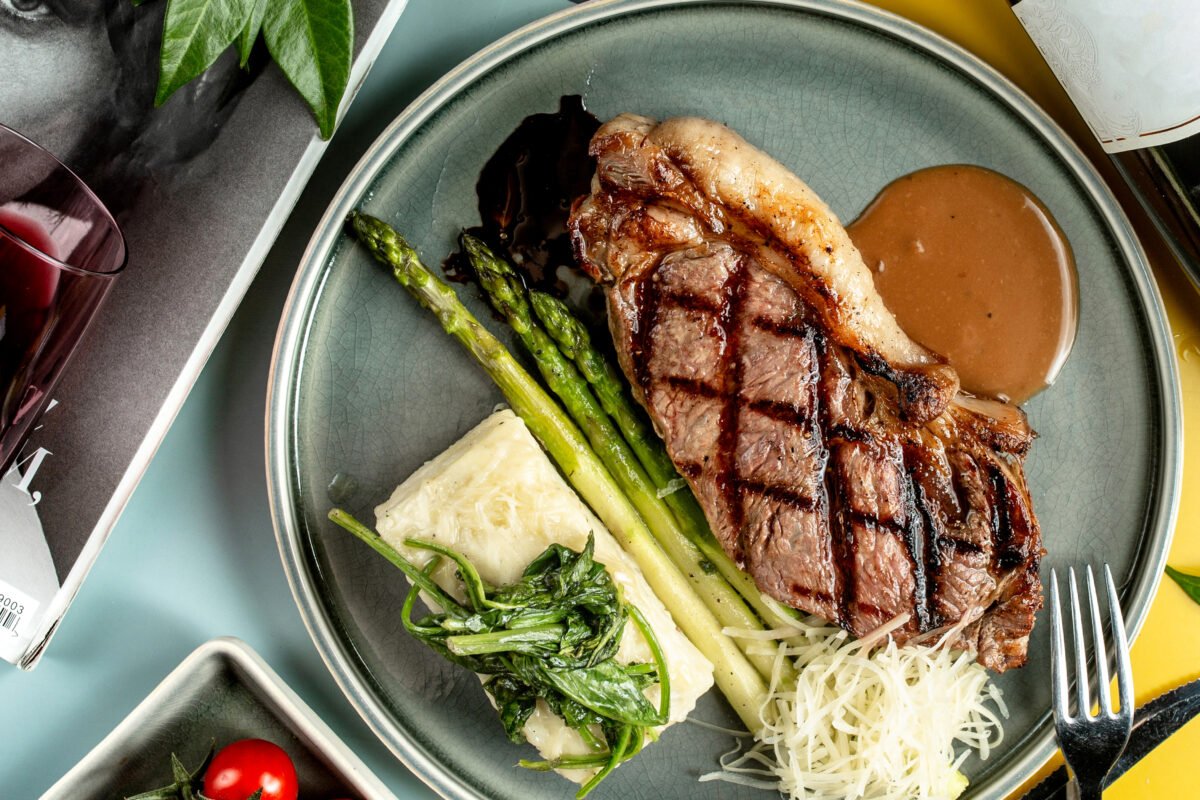 Top view of beef steak served with boiled asparagus spinach and sauce